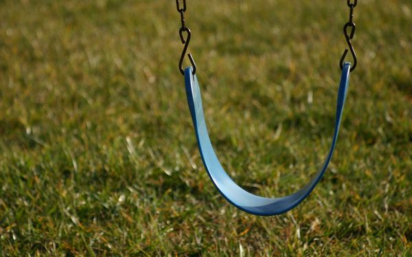 An empty swing over green grass